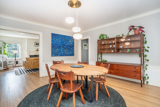 26 Ridgewood Rd, West Hartford, CT 06107 - dining room featuring light wood-type flooring, crown molding, a fireplace, and a wainscoted wall