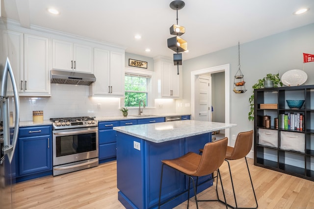 26 Ridgewood Rd, West Hartford, CT 06107 - kitchen featuring appliances with stainless steel finishes, blue cabinetry, a sink, under cabinet range hood, and light wood-style flooring
