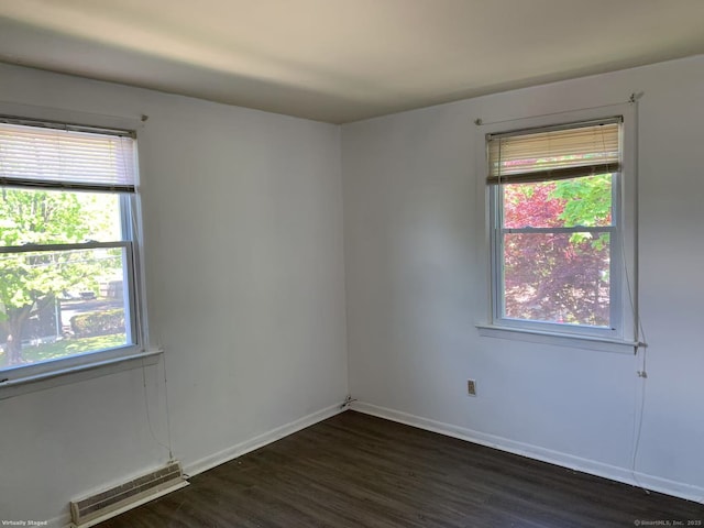 spare room featuring healthy amount of natural light, dark wood-style floors, and baseboards