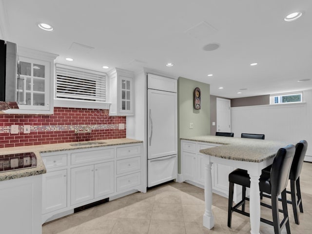 226 Alberta St, Fairfield, CT 06825 - kitchen featuring paneled refrigerator, white cabinetry, a peninsula, a sink, and tasteful backsplash