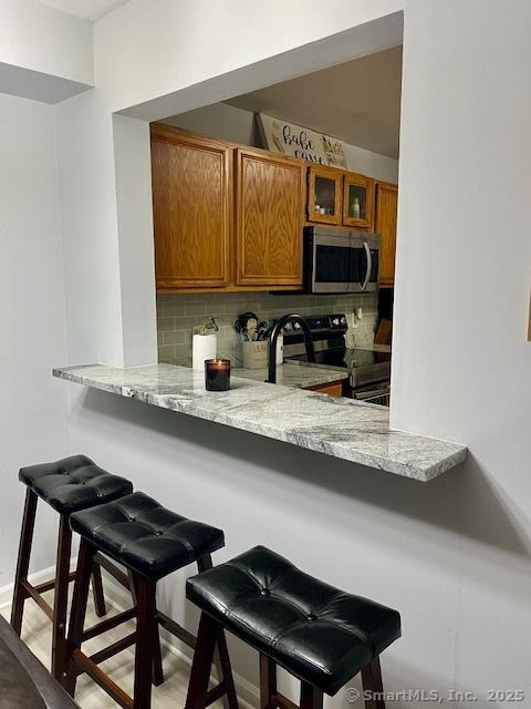 6 Hakim St Unit 2-6, Danbury, CT 06810 - kitchen featuring stainless steel appliances, brown cabinets, decorative backsplash, and a breakfast bar