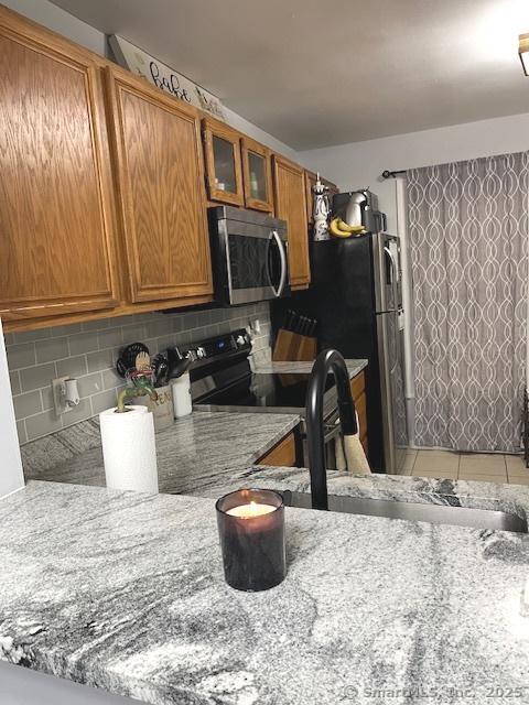 6 Hakim St Unit 2-6, Danbury, CT 06810 - kitchen with stainless steel microwave, brown cabinetry, decorative backsplash, black electric range oven, and glass insert cabinets