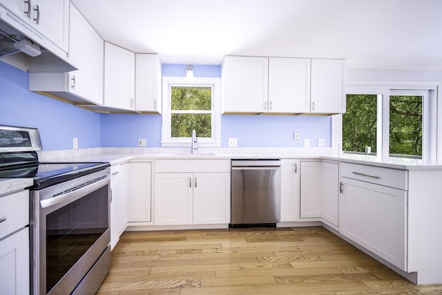kitchen featuring stainless steel appliances, under cabinet range hood, a sink, white cabinetry, and light wood-style flooring