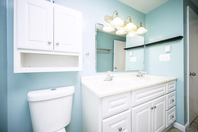 full bath with toilet, double vanity, and a chandelier