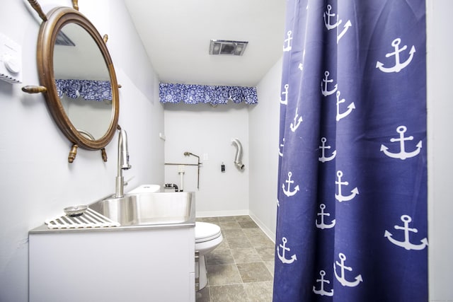 bathroom featuring toilet, vanity, and baseboards