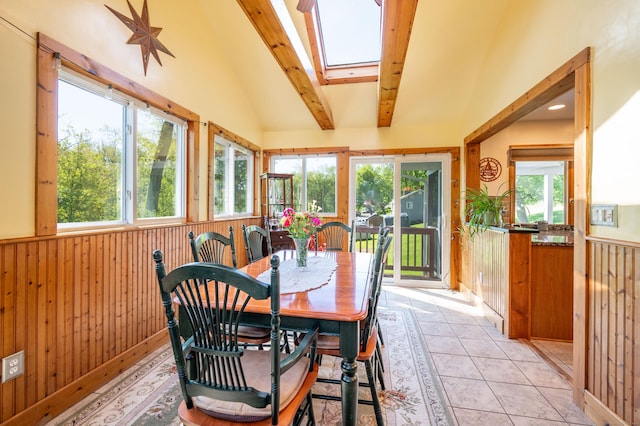 dining space featuring wooden walls, a skylight, wainscoting, and light tile patterned floors