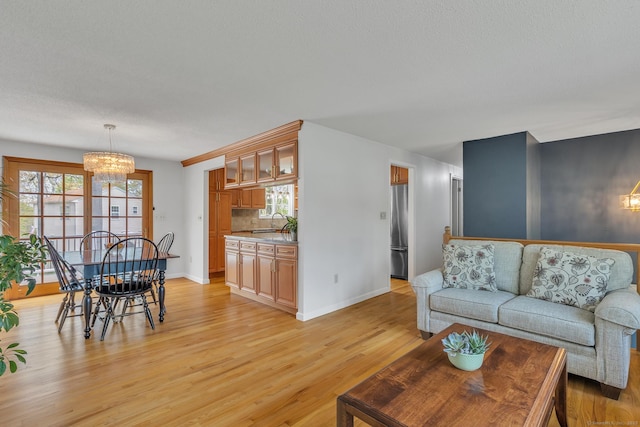 living room with a chandelier, light wood-style floors, and baseboards