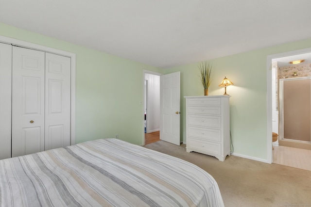 bedroom with light carpet, baseboards, a closet, and ensuite bathroom