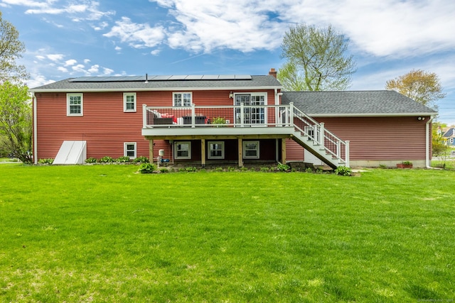 back of property with a wooden deck, a lawn, stairs, and solar panels