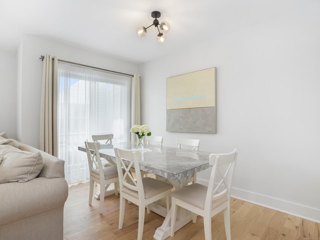 dining room with light wood-style flooring, baseboards, and a chandelier