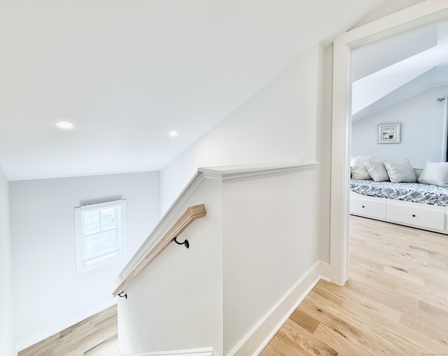 corridor with light wood-style floors, an upstairs landing, recessed lighting, baseboards, and lofted ceiling