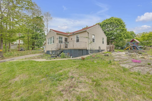 back of house with a playground and a yard