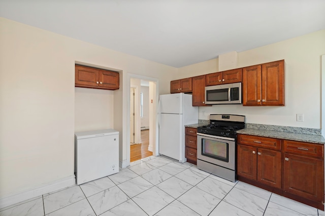 kitchen featuring stainless steel appliances, light marble finish flooring, light stone countertops, and a baseboard heating unit