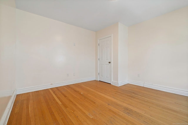 spare room featuring baseboards and light wood-style floors