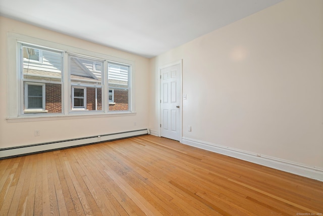 spare room featuring light wood-style floors, baseboards, and baseboard heating