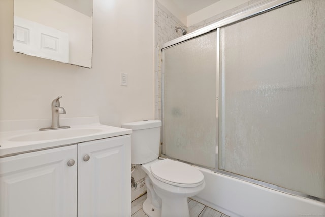 bathroom featuring toilet, vanity, and shower / bath combination with glass door