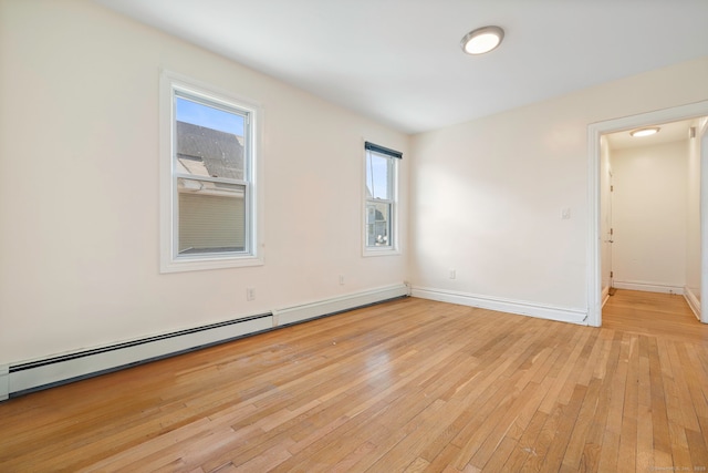empty room with a baseboard heating unit, light wood-style floors, and baseboards