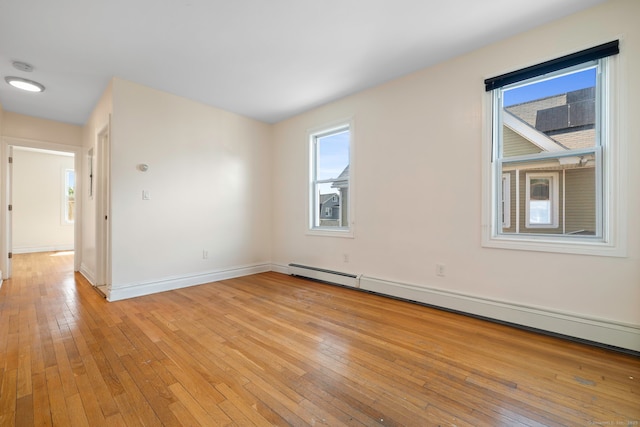 unfurnished room with a baseboard radiator, light wood-style floors, plenty of natural light, and baseboards