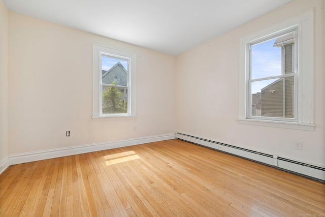 unfurnished room featuring a baseboard radiator, light wood-style flooring, and baseboards