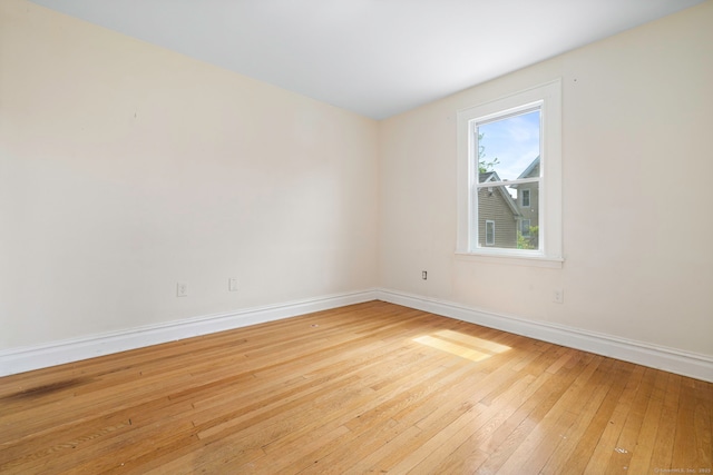 unfurnished room with hardwood / wood-style floors and baseboards