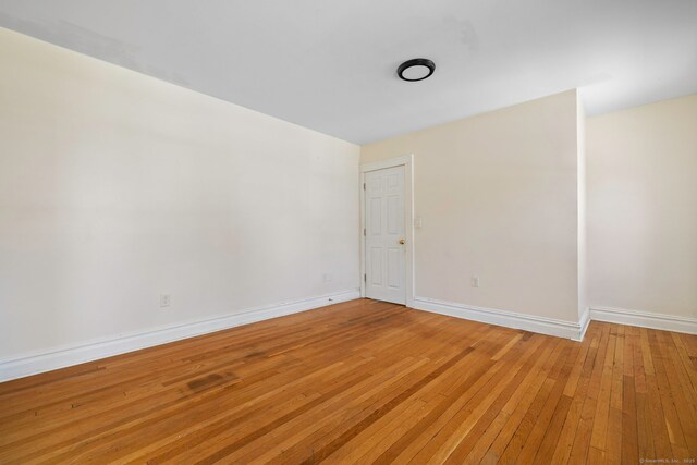 spare room featuring light wood-type flooring and baseboards