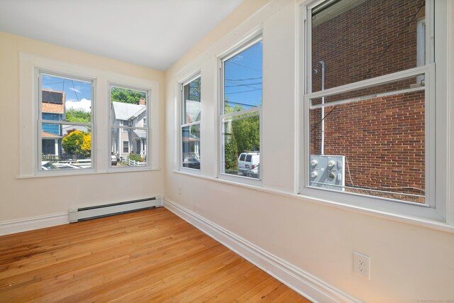 unfurnished room featuring a baseboard radiator, wood finished floors, and baseboards
