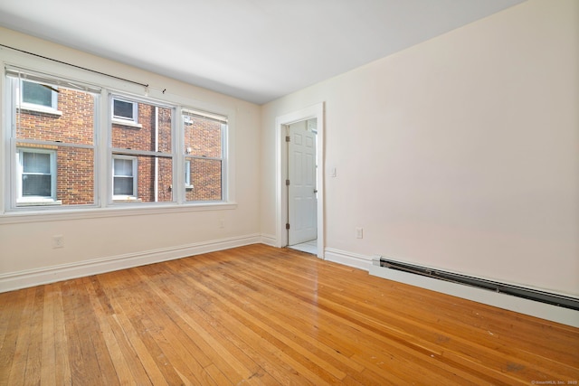 spare room with light wood finished floors, baseboards, and a baseboard heating unit