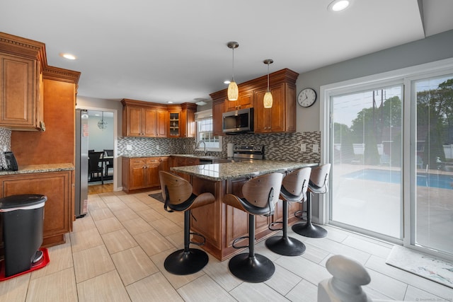 105 Reussner Rd, Southington, CT 06489 - kitchen featuring stainless steel appliances, brown cabinetry, backsplash, a breakfast bar, and a peninsula