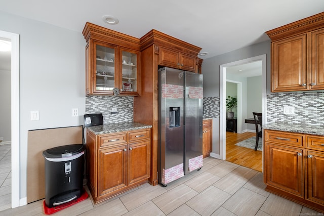 105 Reussner Rd, Southington, CT 06489 - kitchen with stainless steel fridge, tasteful backsplash, brown cabinetry, stone countertops, and glass insert cabinets