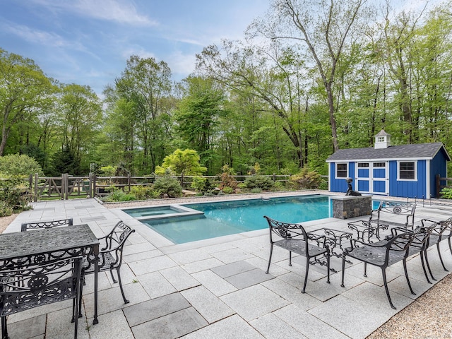 view of swimming pool with a patio, an outbuilding, outdoor dining space, fence, and a storage shed