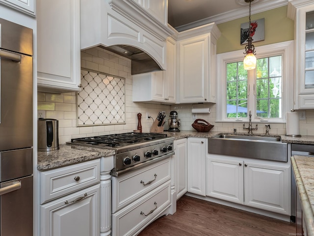 kitchen featuring stainless steel gas cooktop, white cabinetry, custom exhaust hood, decorative backsplash, and a sink