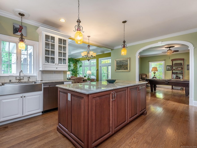 kitchen featuring stainless steel dishwasher, arched walkways, a sink, glass insert cabinets, and white cabinets