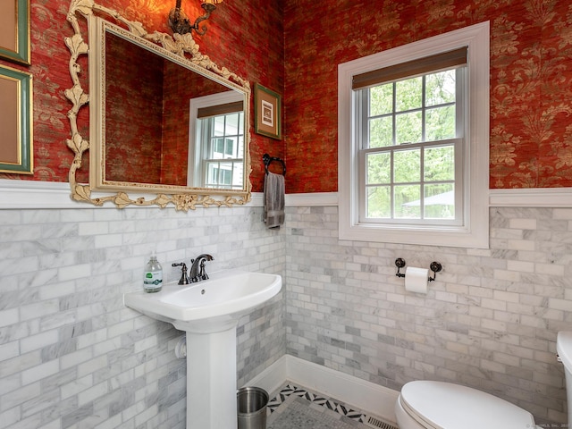 half bathroom featuring toilet, wainscoting, and wallpapered walls