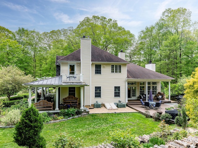 rear view of house with a patio, a chimney, a yard, and central AC