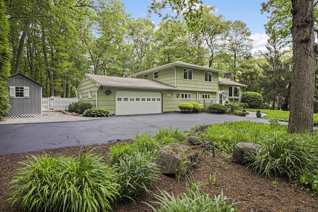 70 Bayne St, Norwalk, CT 06851 - view of front of house with an attached garage, driveway, a chimney, and view of scattered trees