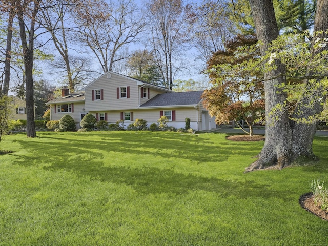 tri-level home featuring a front lawn and a chimney