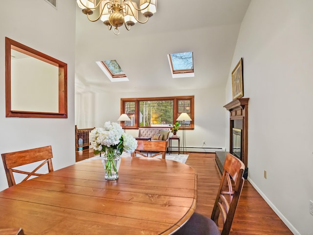 dining area with a skylight, a baseboard radiator, a chandelier, baseboards, and wood finished floors