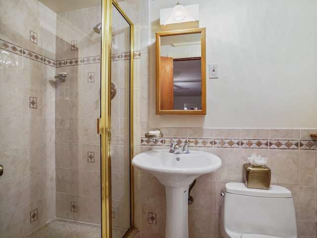 full bath featuring a shower stall, toilet, tile walls, and wainscoting