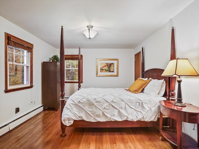 bedroom with baseboard heating and wood finished floors