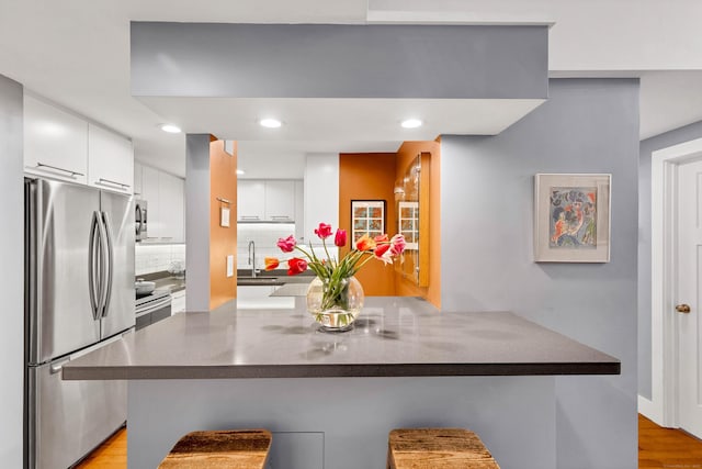 4 Coggswell St Unit 2, Stonington, CT 06379 - kitchen featuring stainless steel appliances, white cabinets, backsplash, modern cabinets, and a kitchen bar