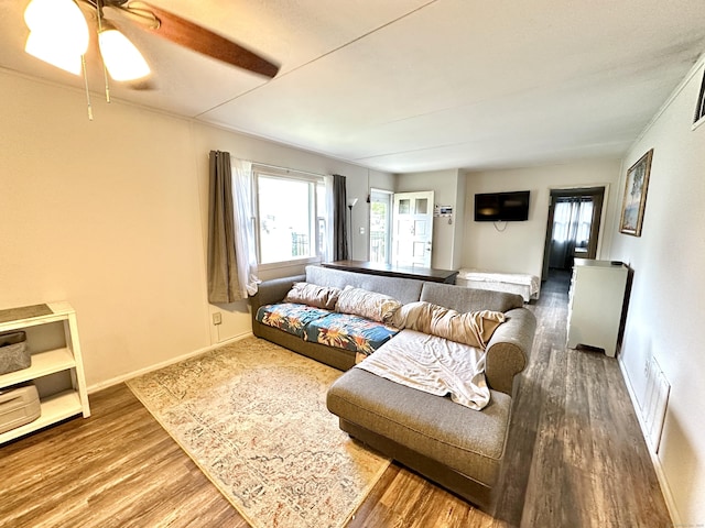 living room with wood finished floors, a ceiling fan, and baseboards
