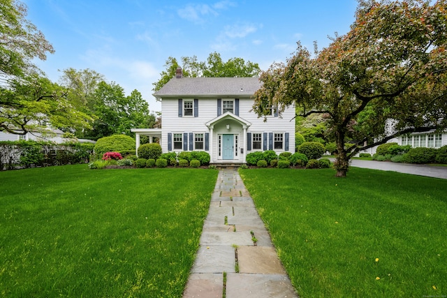 colonial house featuring a front lawn and a chimney