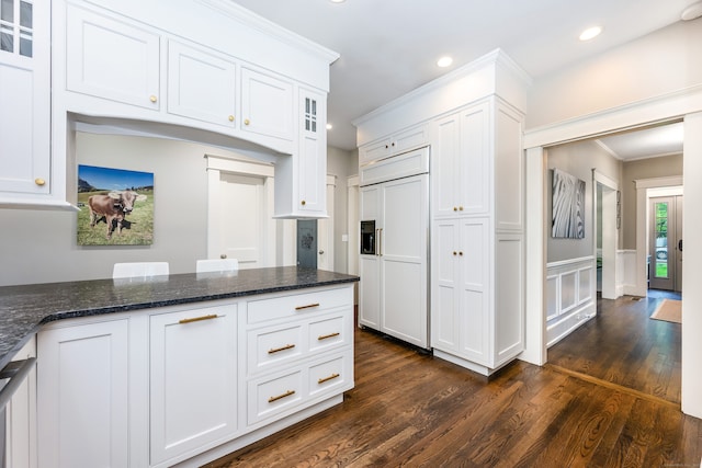 kitchen featuring paneled fridge, white cabinetry, dark wood-style floors, recessed lighting, and dark stone counters