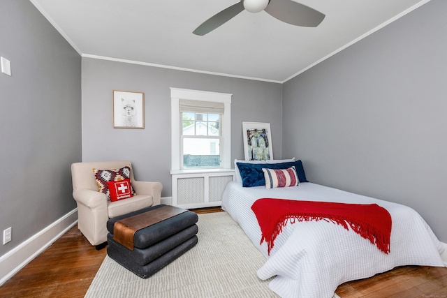 bedroom featuring wood finished floors, crown molding, baseboards, radiator, and a ceiling fan