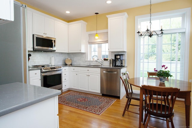 kitchen with stainless steel appliances, a sink, a chandelier, backsplash, and dark countertops
