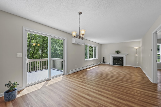 5 Nutmeg Ln, East Hampton, CT 06424 - unfurnished living room with a wall unit AC, baseboard heating, wood finished floors, a chandelier, and a textured ceiling