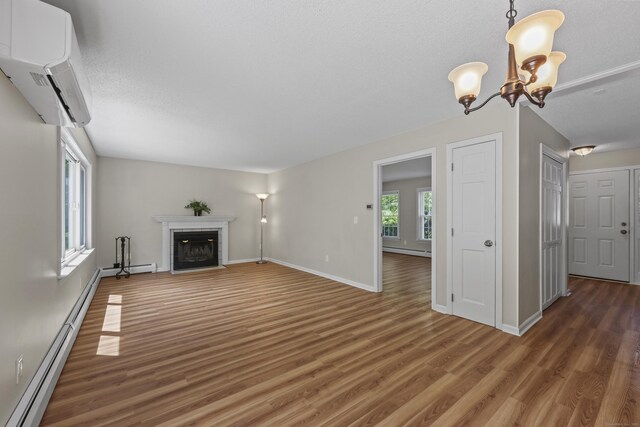 5 Nutmeg Ln, East Hampton, CT 06424 - unfurnished living room with a baseboard heating unit, wood finished floors, a fireplace with flush hearth, a chandelier, and baseboards