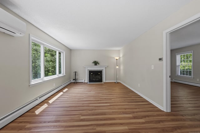 5 Nutmeg Ln, East Hampton, CT 06424 - unfurnished living room featuring a wall mounted AC, a baseboard radiator, wood finished floors, a fireplace with flush hearth, and baseboards