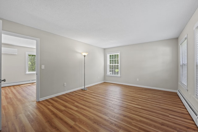 5 Nutmeg Ln, East Hampton, CT 06424 - spare room with a baseboard radiator, a wall mounted AC, wood finished floors, and plenty of natural light