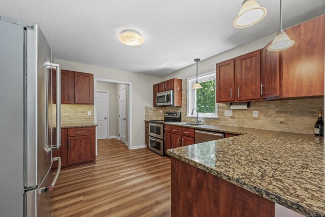 5 Nutmeg Ln, East Hampton, CT 06424 - kitchen featuring appliances with stainless steel finishes, a sink, light wood-style flooring, tasteful backsplash, and pendant lighting